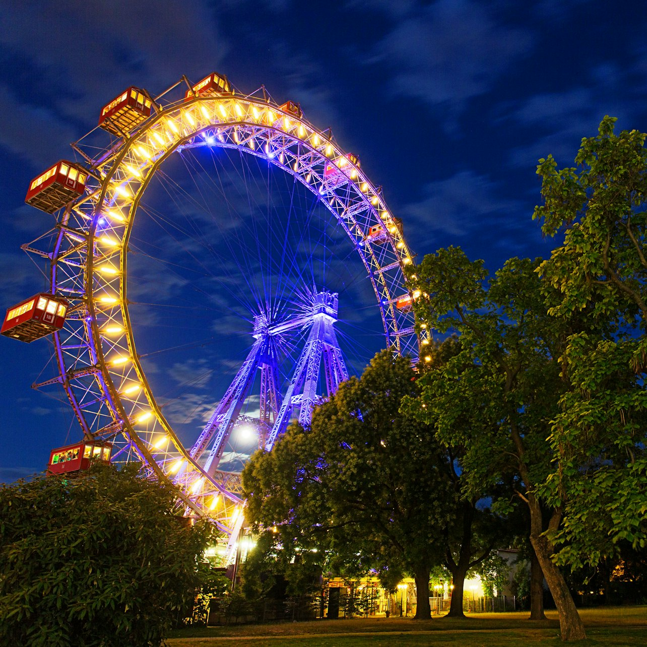 Soaring high above Vienna the Giant Ferris Wheel invites you to enjoy stunning city views at night where illuminated gondolas create a picturesque scene against the skyline.