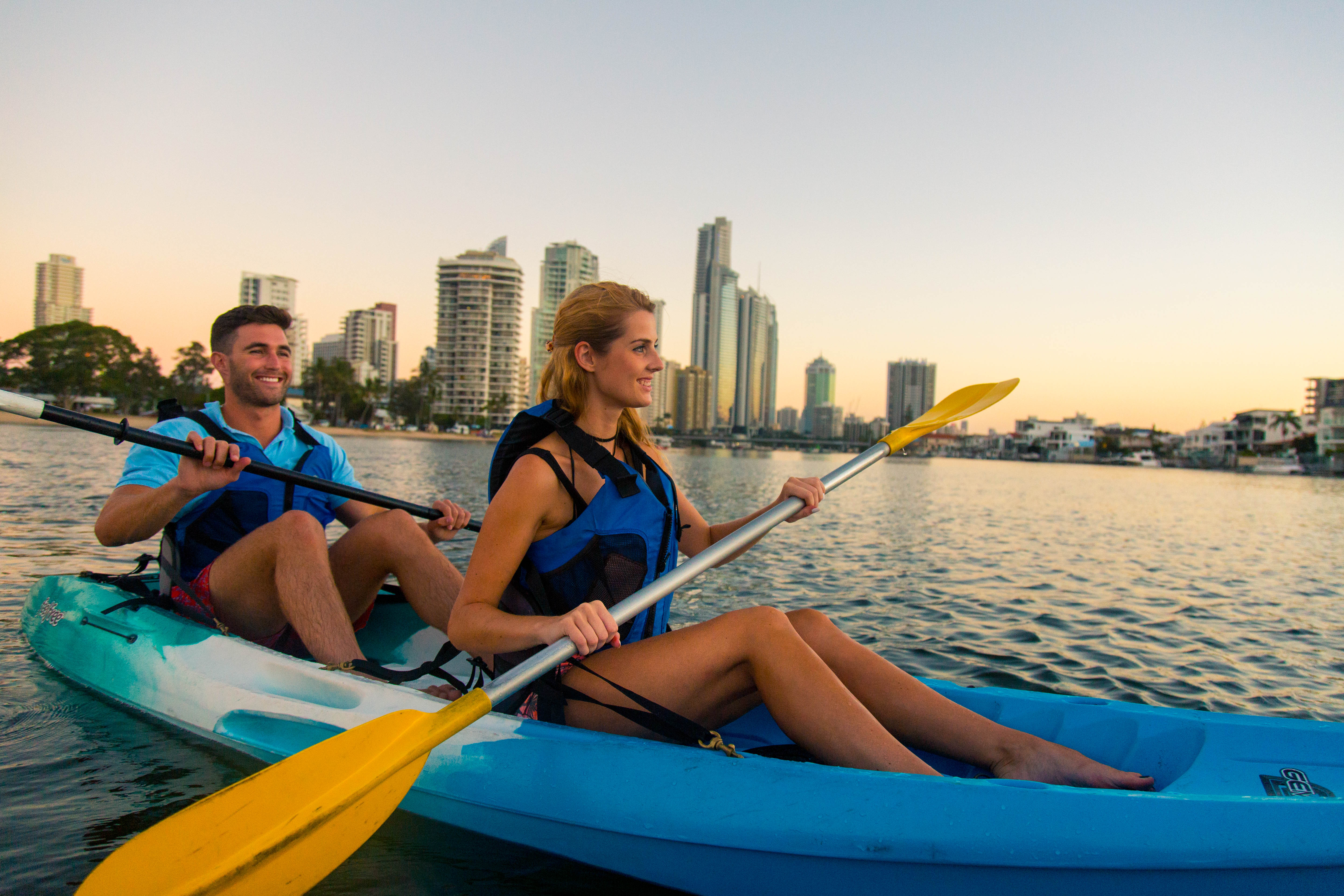 Kayaking through serene waters paddle alongside nature as city skyscrapers rise in the background making every moment a delightful exploration of Gold Coast's beauty and tranquility.