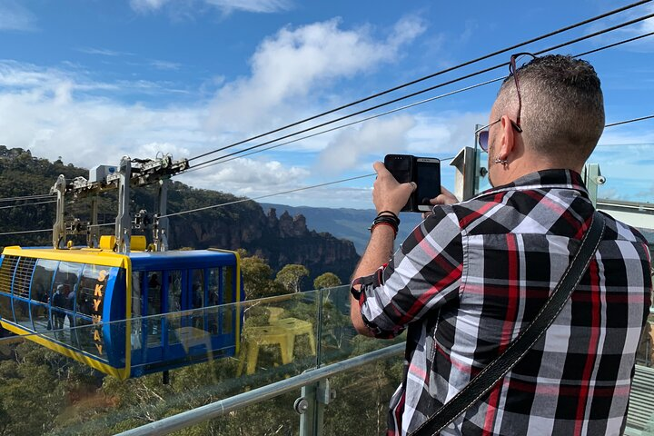 Experience stunning views as you glide through the Blue Mountains aboard a scenic cable car capturing unforgettable moments amidst breathtaking landscapes on a memorable small group tour.