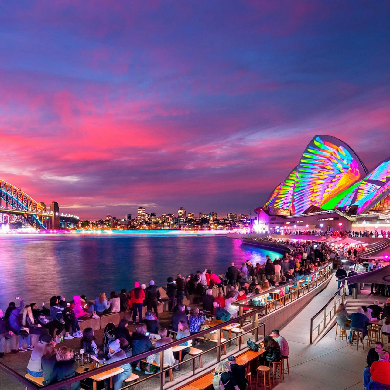 Experience Sydney's stunning Vivid light display from a luxurious cruiser savoring complimentary drinks and delicious food while surrounded by illuminated landmarks and a delightful ambiance.