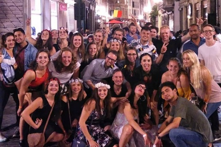 Join a lively group of travelers as they enjoy Brussels' nightlife making new connections while exploring local bars sharing laughs and savoring delicious drinks throughout an unforgettable evening.