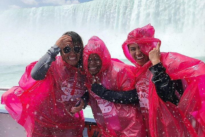 Visitors laugh and enjoy the mist aboard a Niagara City Cruises boat.
