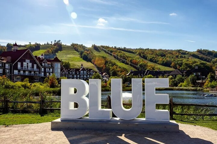 Iconic BLUE sign at Blue Mountain Village with scenic ski hills behind.