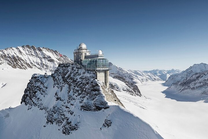 Experience breathtaking views from Jungfraujoch as you stand amidst towering peaks and endless glaciers with the majestic Alps creating a stunning backdrop for your Swiss adventure.