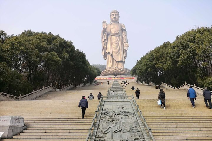 Stand in awe before the towering Lingshan Grand Buddha an impressive symbol of spirituality while exploring the serene pathways leading to peaceful reflections on Taihu Lake's shimmering waters.