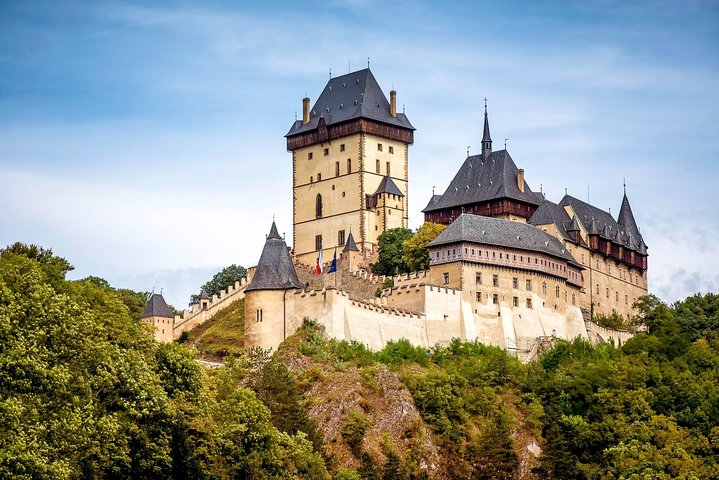 Experience the charm of Karlstejn Castle set against lush greenery on a journey from Munich to Prague discovering rich history and stunning landscapes along the way.