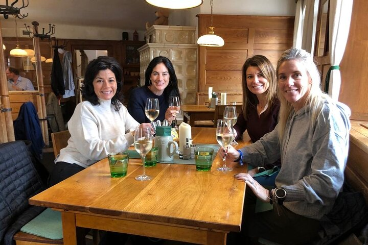 Gather around a wooden table in Salzburg enjoying delightful local dishes and drinks with friends. Savor the perfect blend of history and cuisine in this charming setting.
