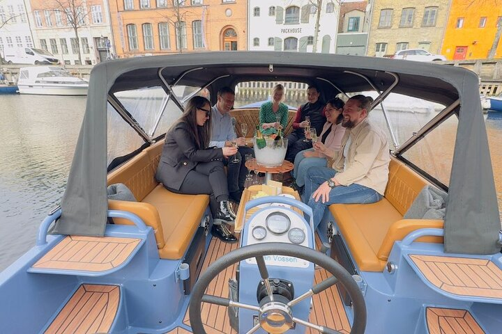 Explore Copenhagen's beauty from the cozy electric boat 'Hygge'. Enjoy local stories and picturesque canals while sharing moments with friends in this unique experience on the water.