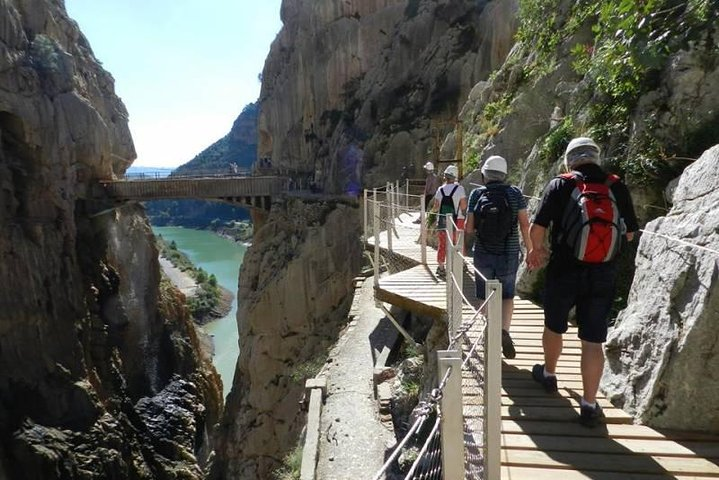 Experience the breathtaking views of the Caminito del Rey where stunning cliffs meet serene waters inviting adventurers to traverse this historic path with friends and fellow explorers.