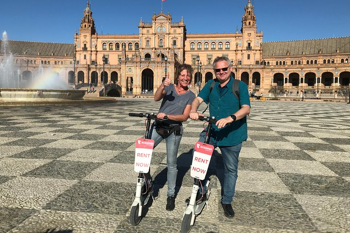 Explore Seville on electric scooters gliding past stunning landmarks like Plaza de España with plenty of time for picturesque stops and cherished memories along the way.