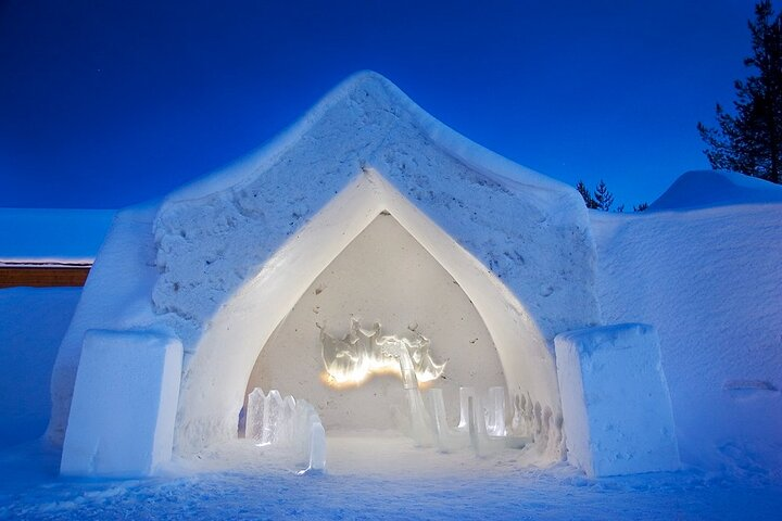 Experience the magical world of ice and snow artistry at the Arctic Snow Hotel where stunning sculptures and cozy igloos await under the vast clear sky of Rovaniemi.