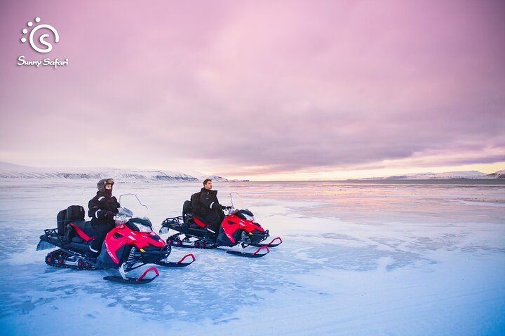Experience the thrill of snowmobiling across a serene frozen lake surrounded by stunning winter landscapes as you embrace local traditions and cozy up with a hearty BBQ.