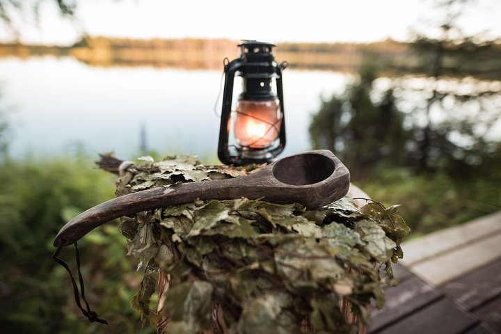 Experience the charm of Lapland with rustic beauty surrounding a serene lake as a glowing lantern and handcrafted wooden spoon evoke a sense of traditional Finnish relaxation.
