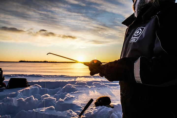 Experience the tranquility of ice fishing on a frozen lake as you connect with nature catch fish and enjoy warm drinks by the campfire in stunning winter scenery.