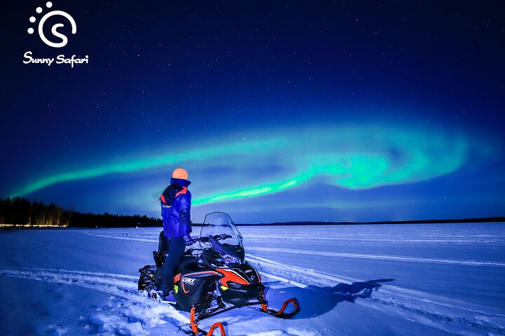 Snowmobiling across pristine frozen lakes travelers gaze up at a spectacular display of the Northern Lights creating an unforgettable connection with nature under a breathtaking night sky.