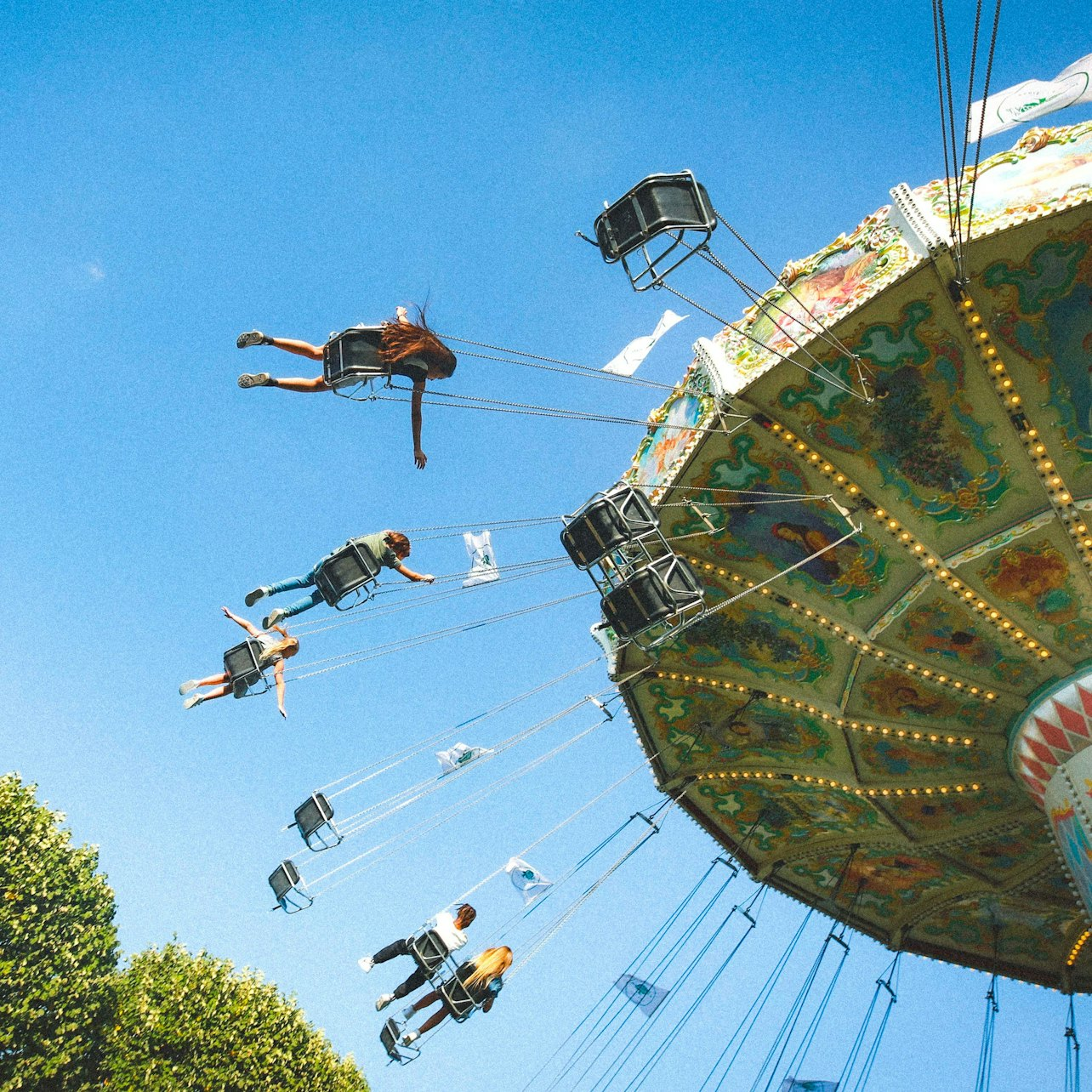 Soar high above the lush greenery of Jardin d'Acclimatation where laughter fills the air as thrill-seekers experience the joy of this delightful swing ride in the heart of Paris.