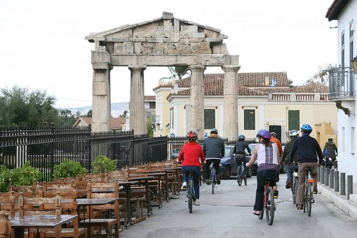 Explore the charm of Athens on two wheels cycling through historic streets capturing stunning views and enjoying a delightful break with coffee and waffles beneath the Acropolis.