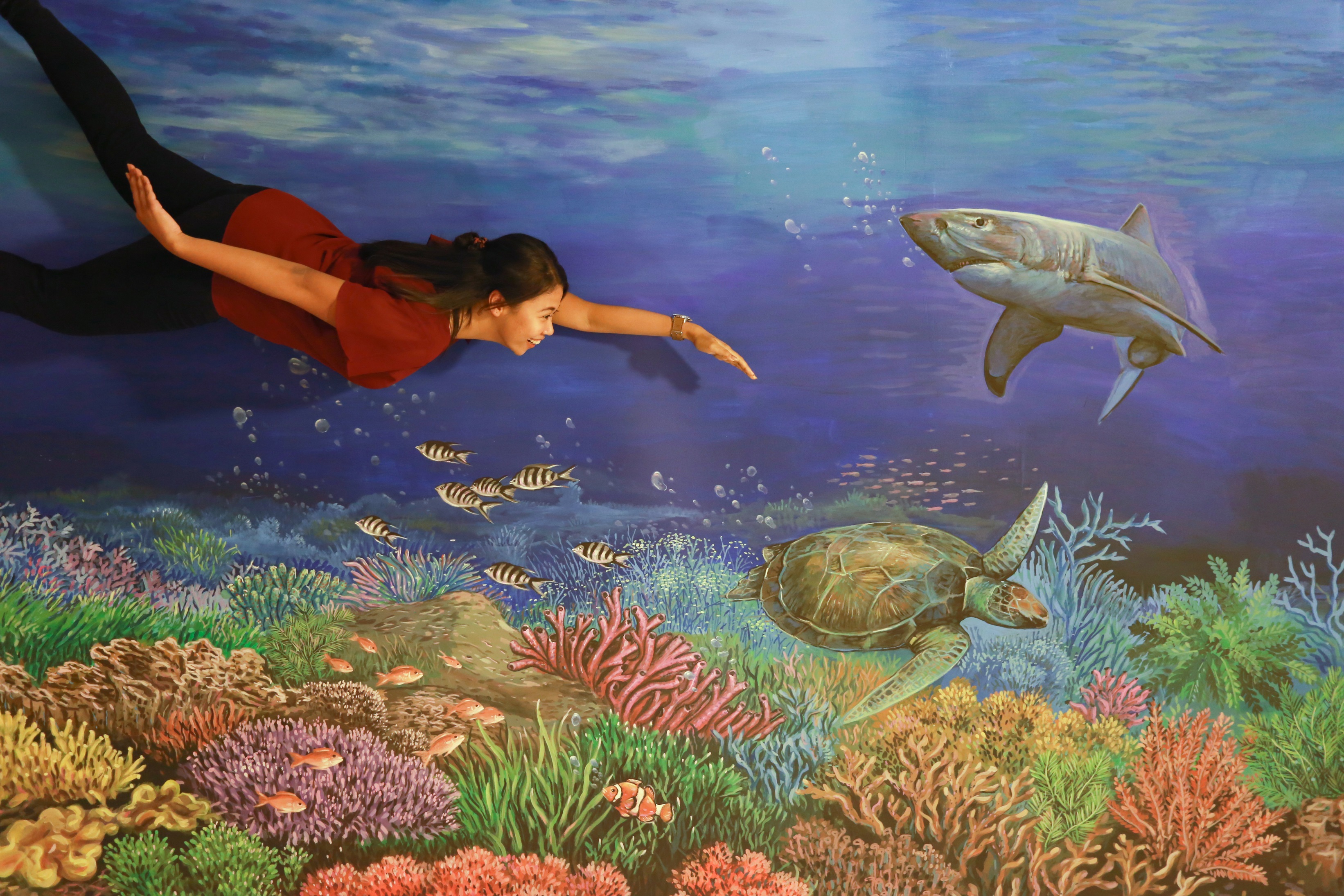 Dive into creativity at Rumah Imaji where you can interact with stunning 3D mural illusions transforming everyday moments into playful adventures among marine life and coral reefs.