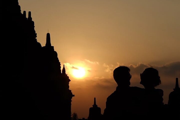 Witness a stunning sunset behind ancient temples creating a perfect backdrop for unforgettable memories in Yogyakarta. Explore iconic sites while enjoying the company of your loved ones.