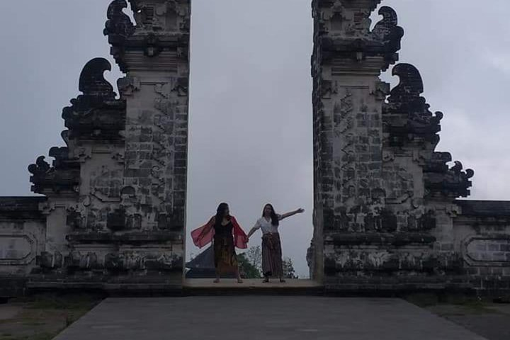 Discover the stunning architecture of Lempuyang Temple where two travelers celebrate the allure of Bali’s spiritual heritage against a backdrop of intricate stonework and lush scenery.