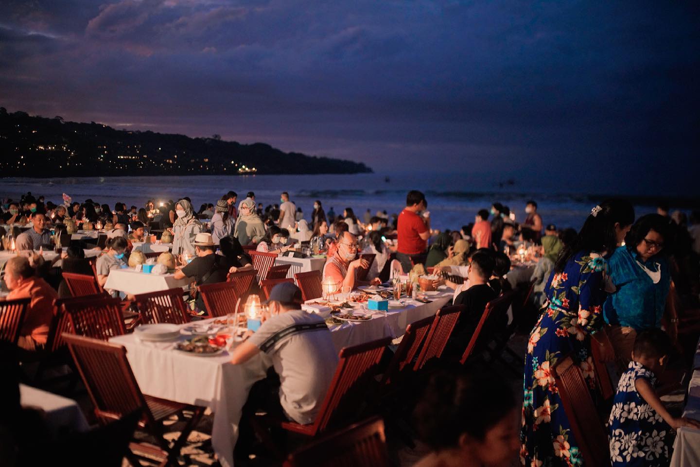 Experience the beachside charm of Teba Cafe in Jimbaran where families and couples gather to enjoy fresh seafood while the sun sets over the stunning Balinese coastline.