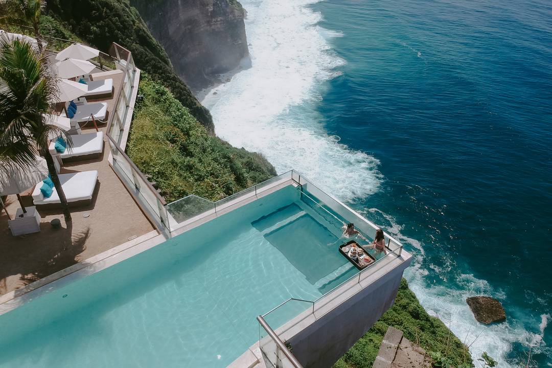 Relax by the stunning glass-bottom infinity pool at The Edge Bali soaking in breathtaking ocean views while enjoying gourmet cuisine and pampering treatments in a luxurious setting.