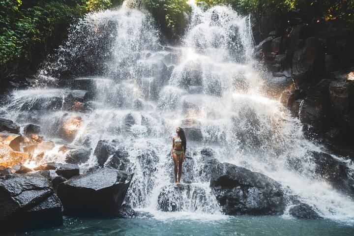 Experience the refreshing embrace of crystal-clear waters cascading down rocks inviting you to explore Ubud's stunning natural wonders and immerse yourself in serene beauty amidst lush greenery.