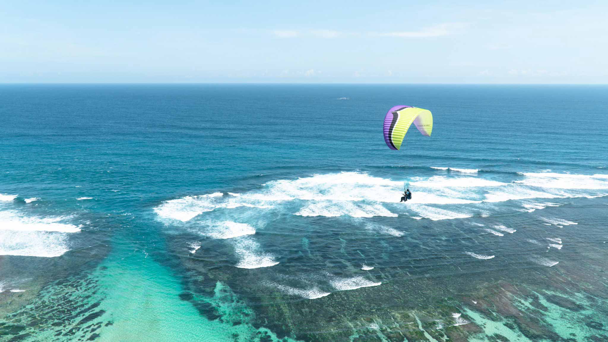 Soar high above hidden temples and limestone cliffs taking in stunning views of the Indian Ocean and lush Balinese landscape during an unforgettable paragliding adventure at Timbis Beach.