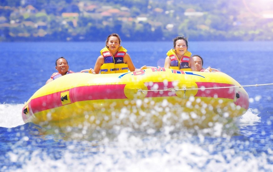 Experience the joy of laughter and splashes as you glide through sparkling waters on a banana boat surrounded by stunning Bali scenery and the thrill of ocean adventures.