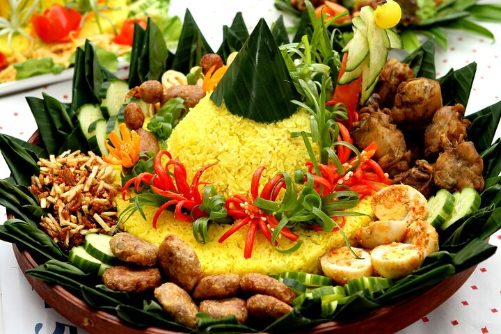 Experience the rich flavors of Indonesia as you prepare traditional Tumpeng yellow rice surrounded by fresh herbs and spices culminating in a delightful homemade meal shared with newfound friends.