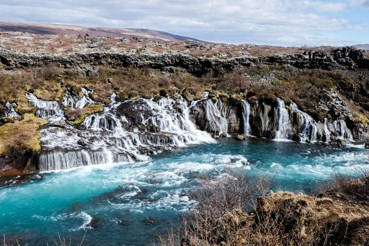 Witness the stunning Hraunfossar waterfalls cascading into the vibrant Hvítá river where nature's artistry creates a breathtaking spectacle for every traveler exploring Borgarfjörður.