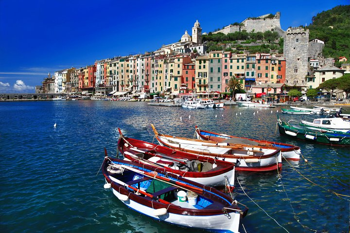 Experience the charm of Cinque Terre as colorful boats gently sway in the serene waters surrounded by picturesque villages and stunning coastal views waiting to be explored.