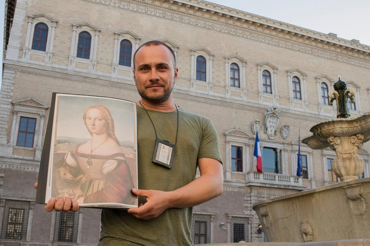 The tour guide holding an image of Giulia Farnese in front of Palazzo Farnese