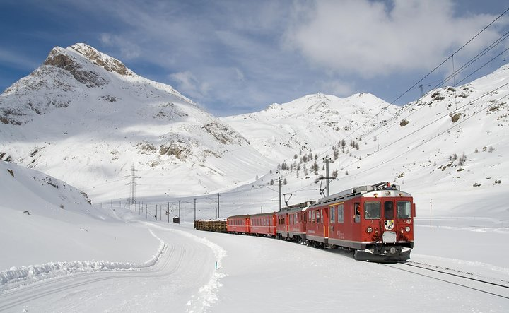 Experience the magic of the Swiss Alps aboard the Bernina Red Train winding through snow-covered peaks and breathtaking vistas on this unforgettable journey to St. Moritz.