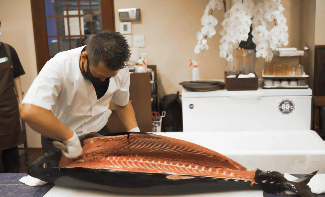Experience the artistry of sushi-making as a skilled chef expertly carves a whole tuna offering an exclusive opportunity to savor endless delicious sashimi paired with traditional sake in Tokyo.