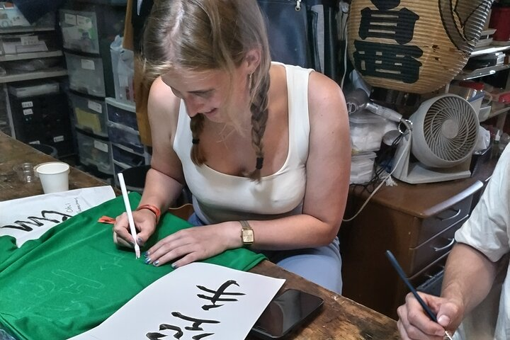 The guest from Holland is a Karate learner so he wanted to write Karate on the T-shirt practicing the Kanji on a peice of paper so seriouly.