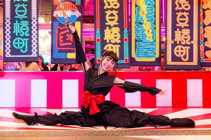 Experience the lively cultural scene in Tokyo as performers showcase traditional art against a backdrop of colorful signage offering a glimpse into the city's rich history and lively urban life.
