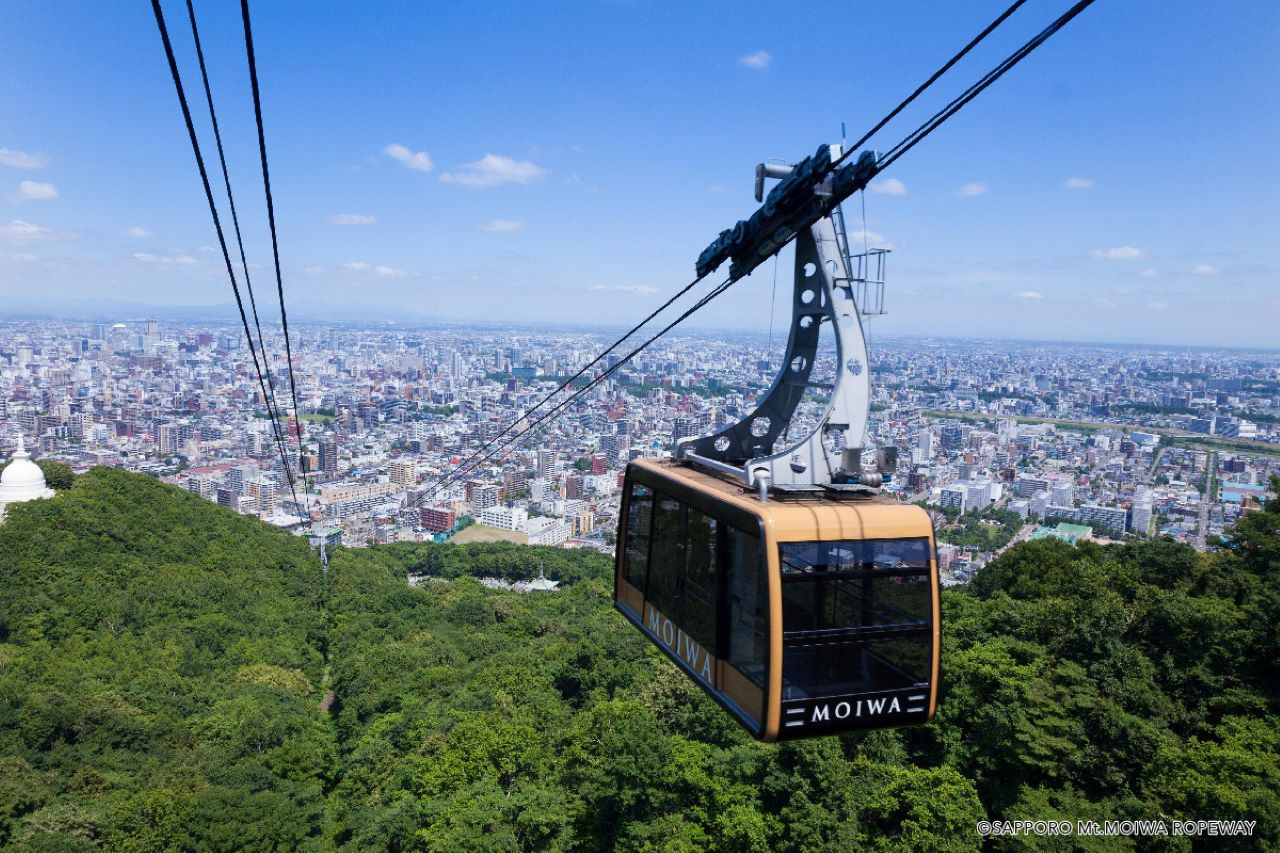 Experience breathtaking views during the Mount Moiwa Ropeway ride soaring above the lush forests and Sapporo's urban landscape leading to a stunning observatory at the peak.