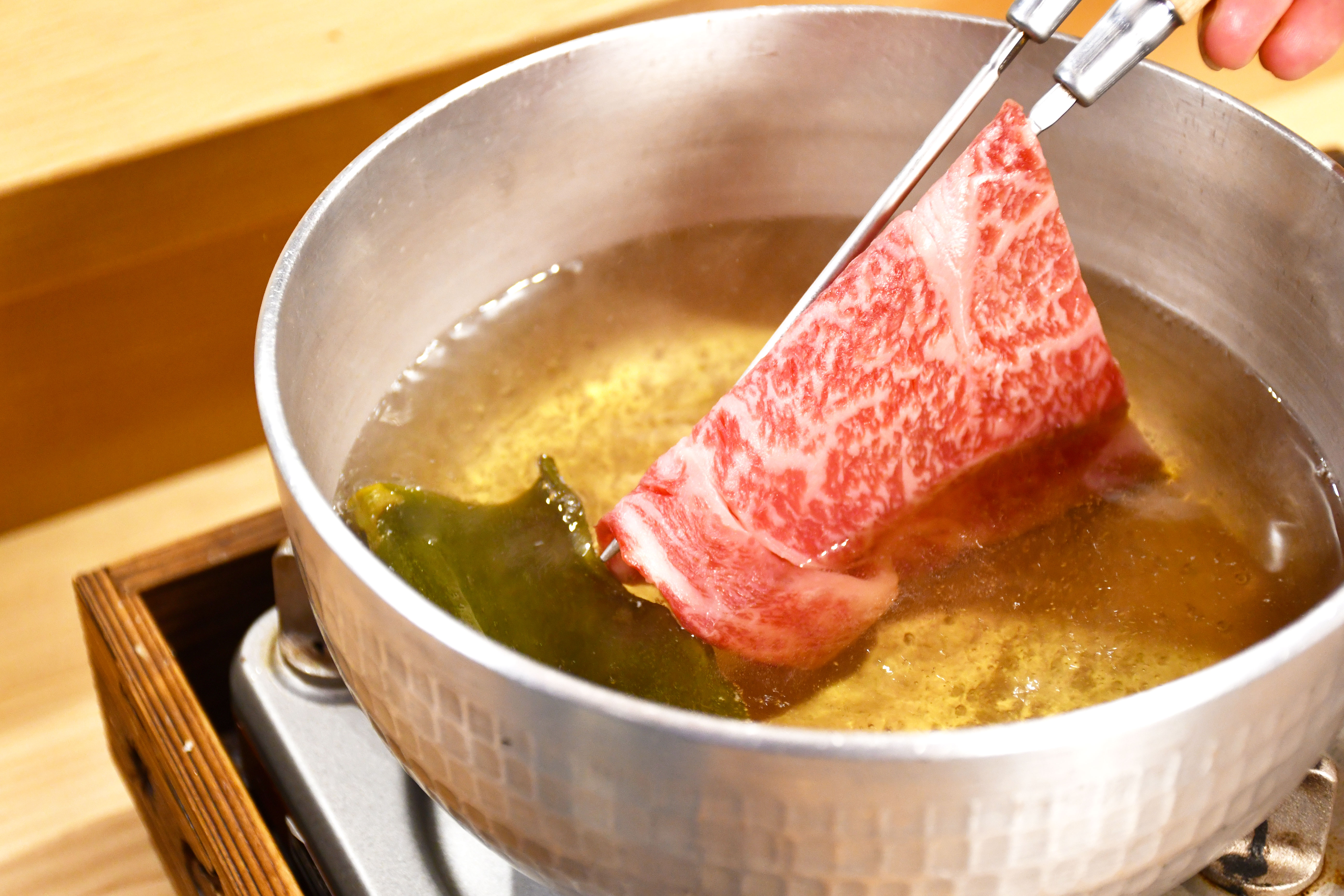 Savor the delicate experience of cooking premium black Wagyu beef in a traditional pot surrounded by the charm of Kyoto's heart perfect for a memorable culinary journey.