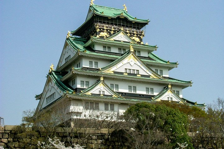 Discover the striking architecture of Osaka Castle surrounded by lush greenery while enjoying a local guide’s insights into the rich history and culture of this remarkable city.