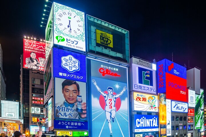 Experience the bustling energy of Dotombori with its dazzling neon signs and iconic Glico mascot surrounded by enticing eateries and shops perfect for indulging in Osaka's culinary delights.