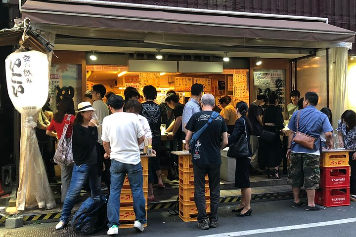 Dive into Tokyo's rich culinary landscape with a local crowd sampling street food delicacies and enjoying a full meal at a traditional izakaya in an unforgettable dining experience.