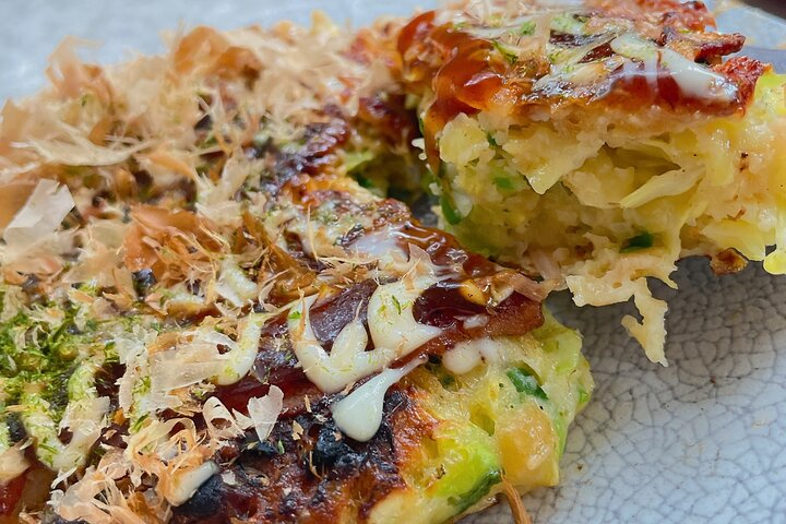 Experience the joy of creating Osaka-style Okonomiyaki customizing your dish with fresh ingredients and enjoying a delicious meal while connecting with local culture and daily life.