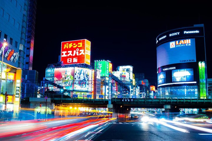 Neon lights pulse in Shinjuku revealing hidden streets and lively encounters. Explore Tokyo's nightlife capturing unique reflections and silhouettes while traversing its dynamic urban landscape.