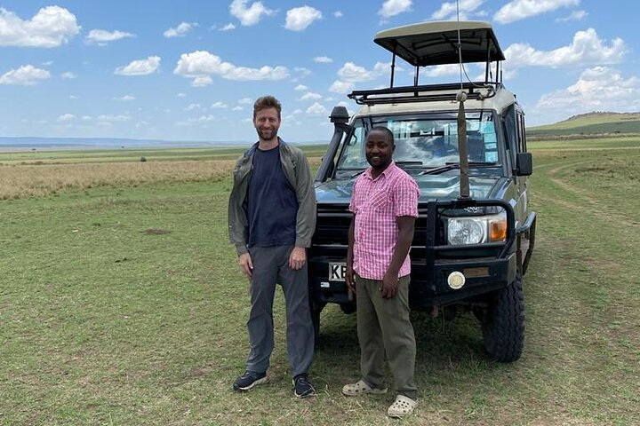 Our Professional Guide posing with the client on the Plains of Maasai Mara after enjoying Picnic Lunch