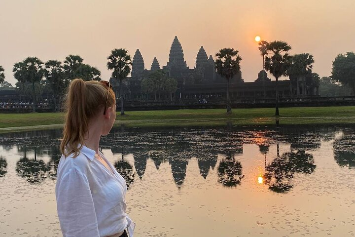 Experience the magical moment as the sun rises over Angkor Wat casting a stunning reflection in the tranquil waters inviting exploration of ancient wonders in the early light.