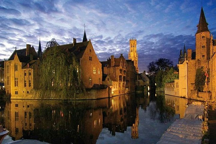 Explore Bruges at twilight where medieval architecture and serene canals create a timeless experience. A perfect day trip from Amsterdam for those seeking history and scenic beauty.