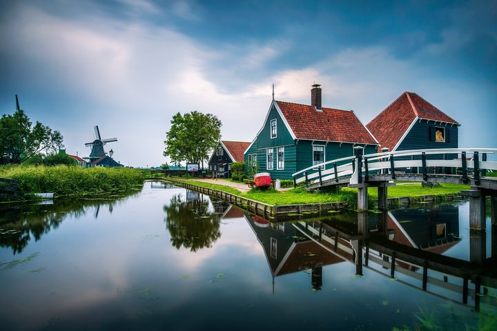 Experience the charm of traditional Dutch windmills and picturesque houses reflected in serene waters offering a glimpse into the beauty and history of the Netherlands. Perfect for explorers seeking genuine adventures.