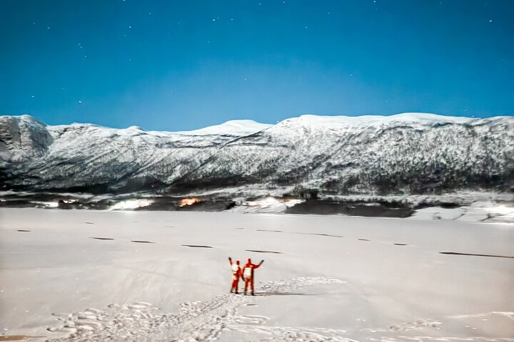 Float under the shimmering Northern Lights in Tromsø's icy waters basking in warmth and wonder followed by cozy moments by the campfire with local treats.