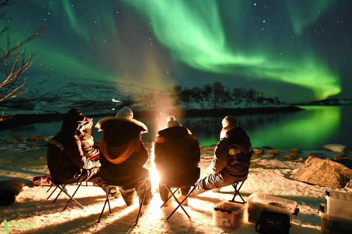 Witness the magical auroras dancing above as you share stories and warmth by a crackling campfire savoring local soup and sipping hot chocolate in pristine Arctic beauty.